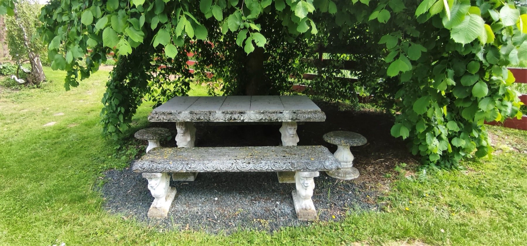 Steinerner Gartentisch im Schatten des Laubbaums